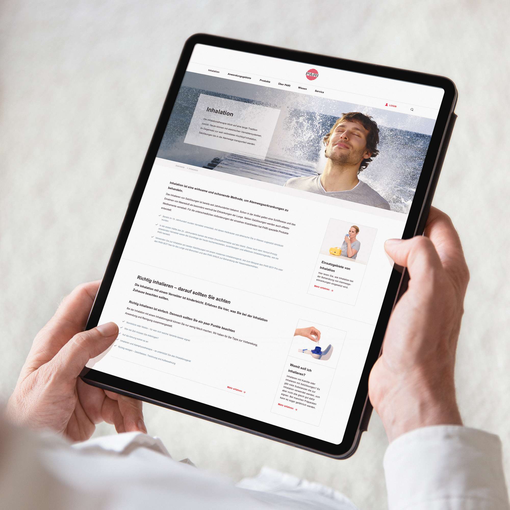 Zwei Hände halten ein Tablet auf dem eine Ansicht der PARI-Website mit mehreren Contentblöcken zu sehen ist